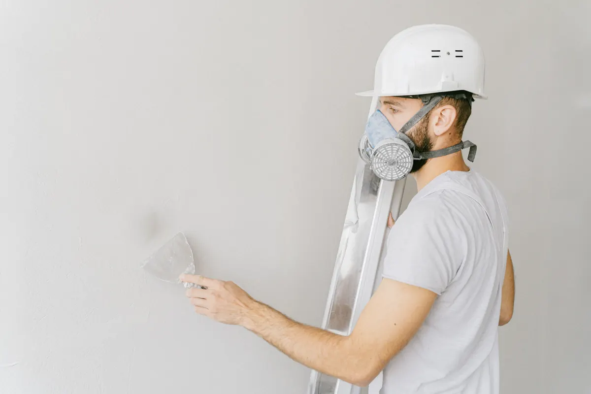 Worker in full protective coveralls, respirator and hard hat carrying out safe removal work