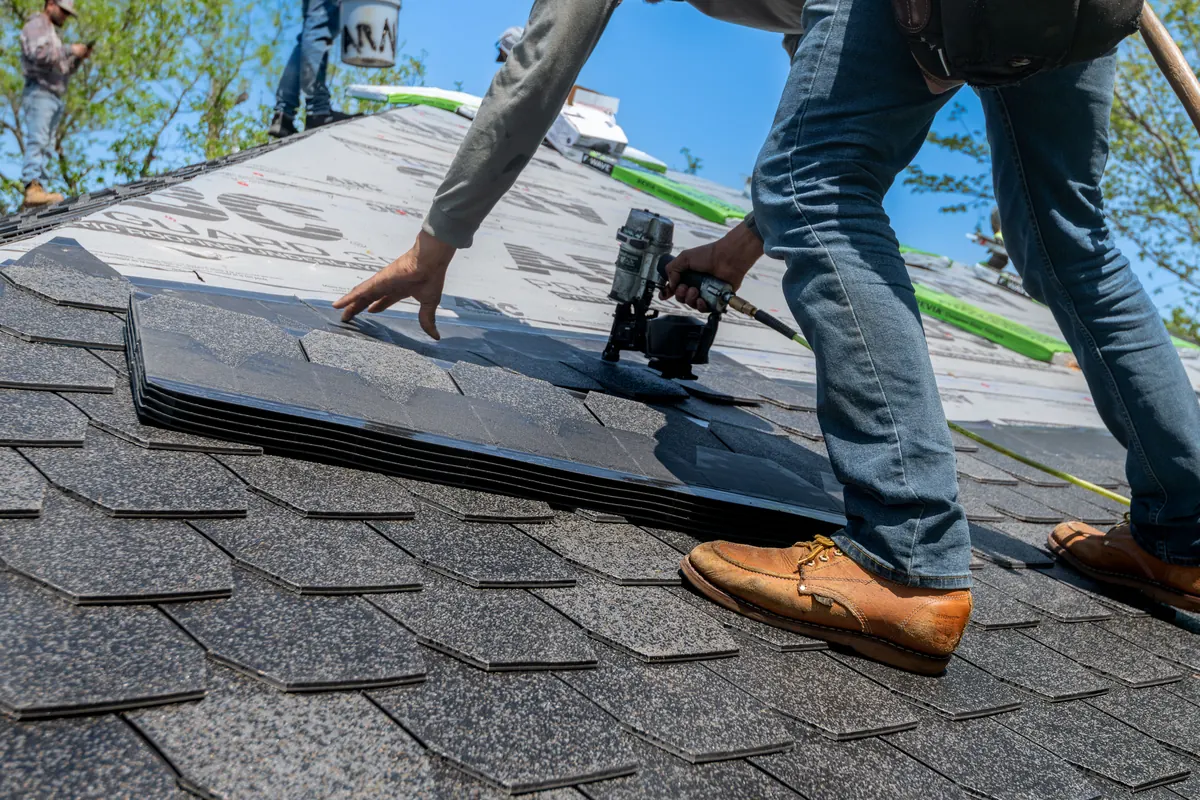 Roofer fitting roof shingles during a roofing repair job
